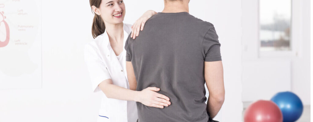 A physical therapist helping a man with back pain due to herniated disc